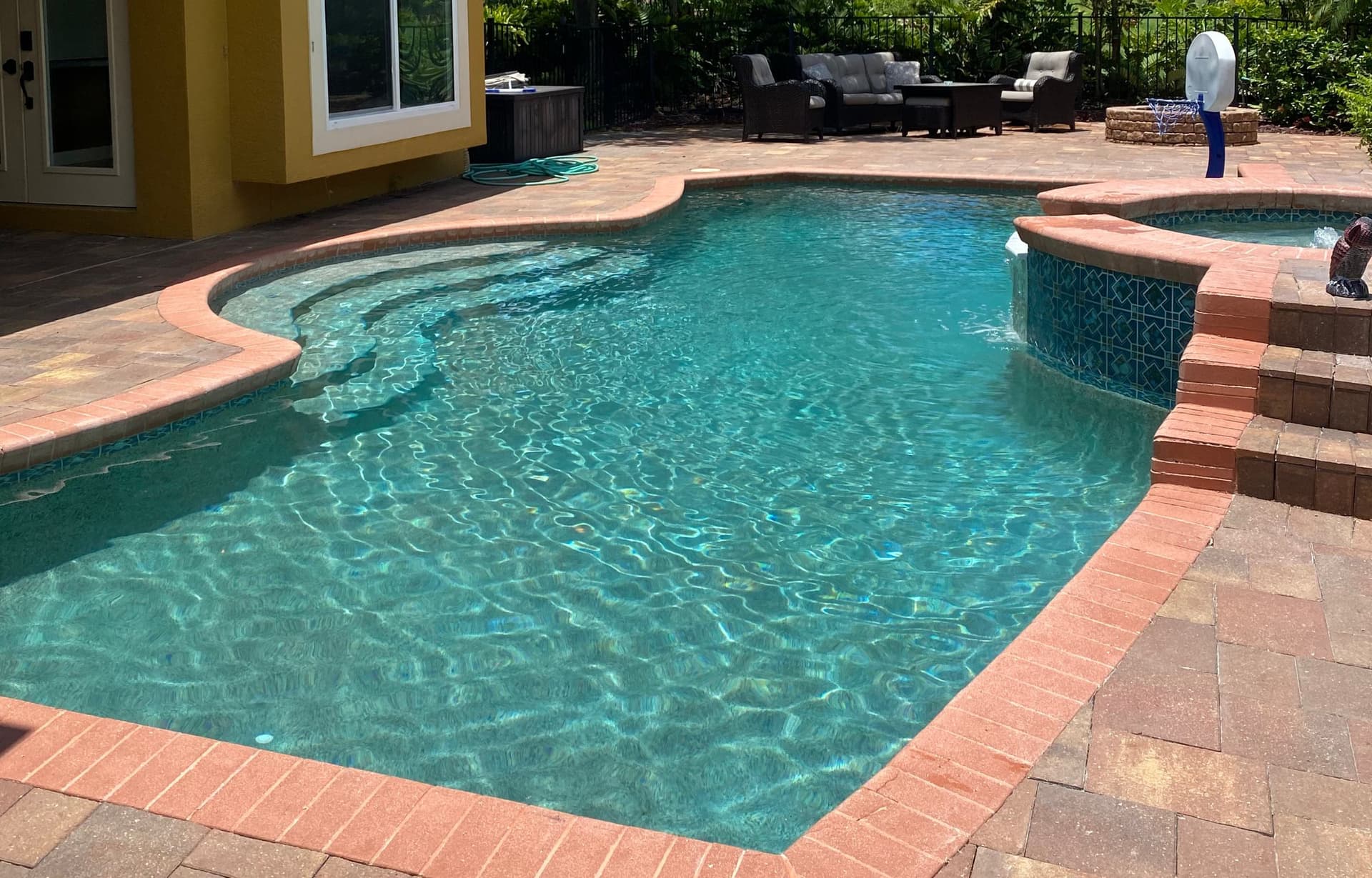 Custom freeform pool with terracotta brick coping and crystal clear water