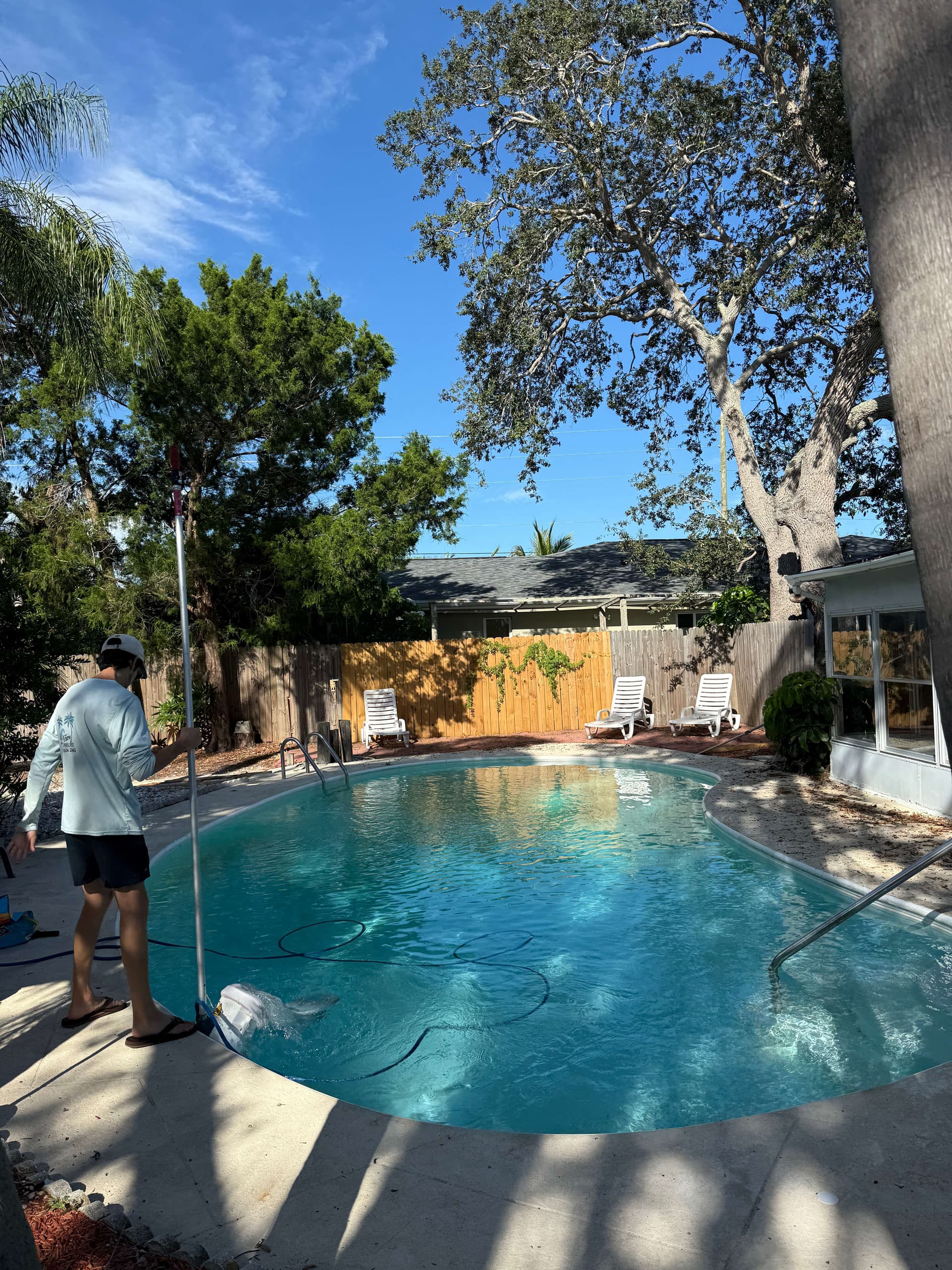 Pool technician performing maintenance service on kidney-shaped pool