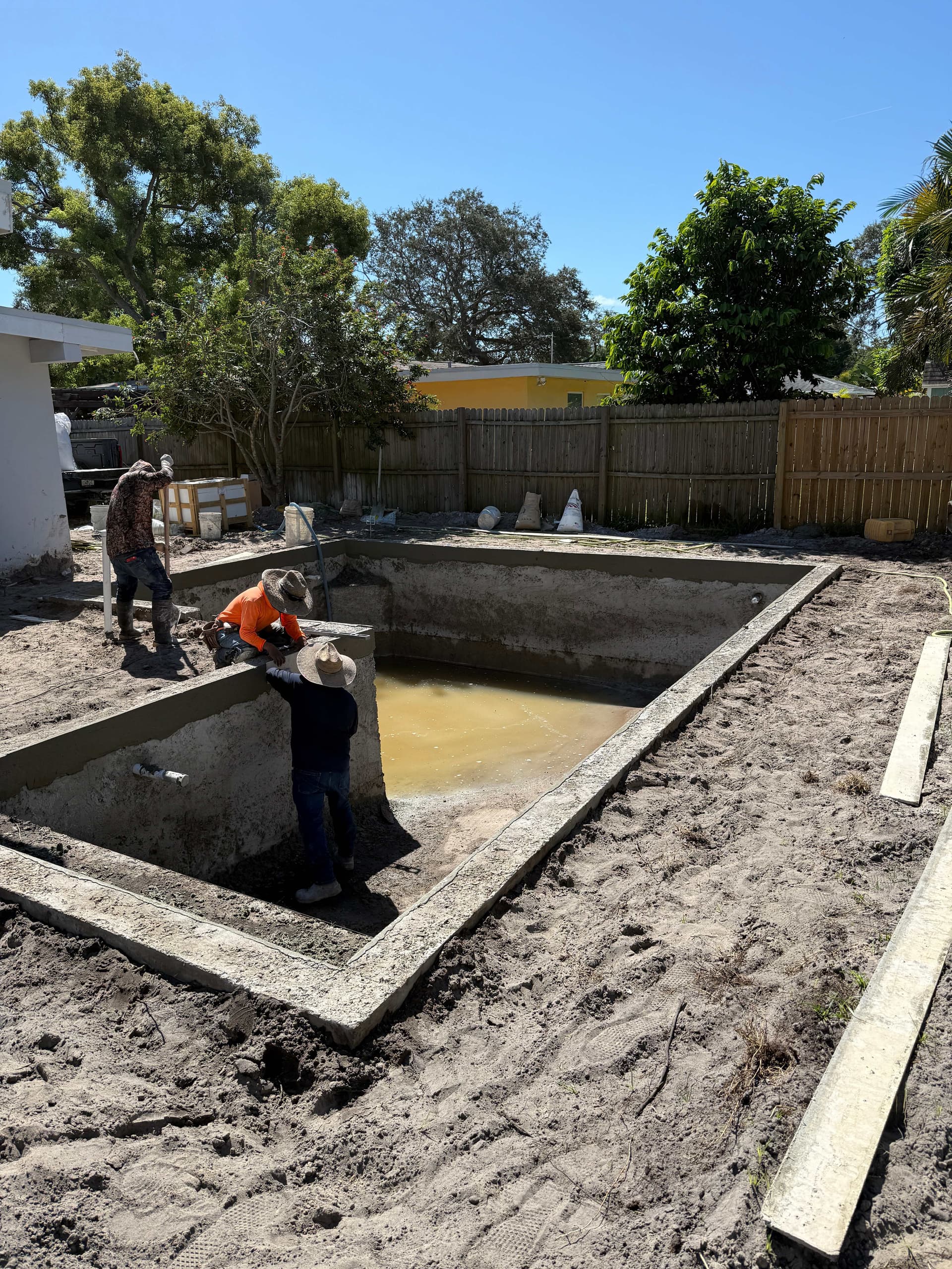 Pool renovation in progress - workers restoring older concrete pool