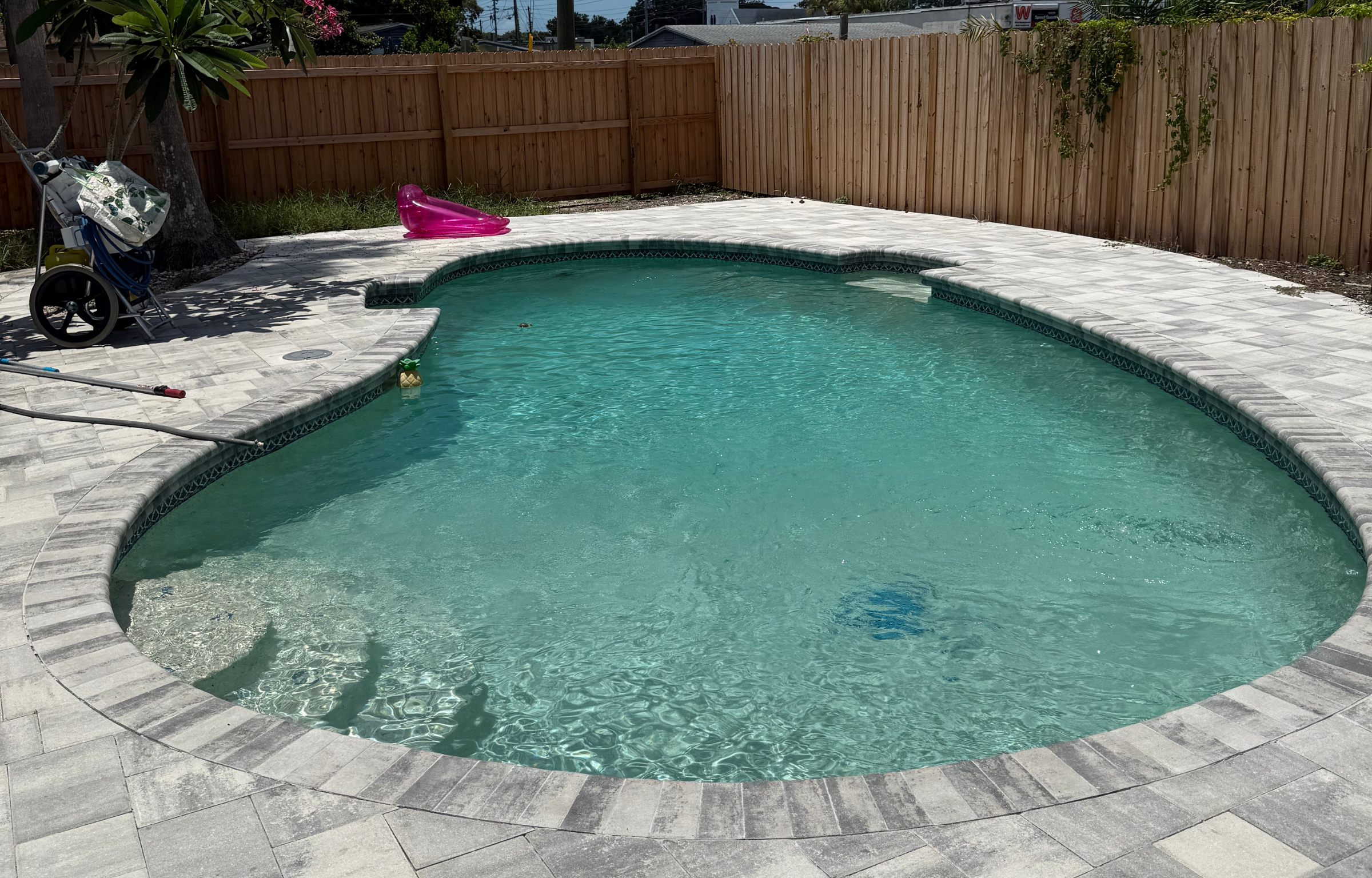 Kidney-shaped pool with elegant paver deck after deep clean
